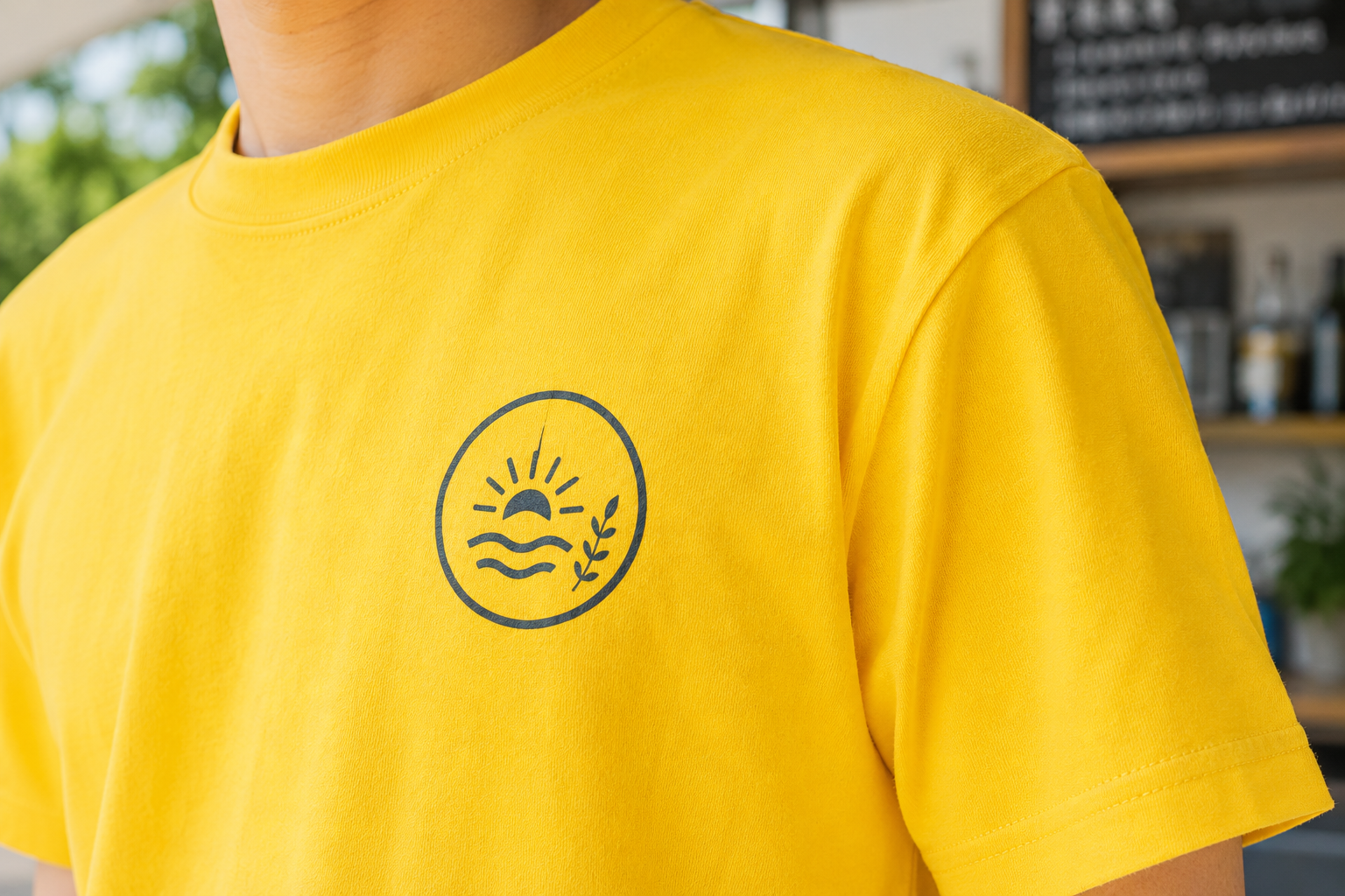 お店のロゴがプリントされた黄色いオリジナルTシャツの胸元クローズアップ